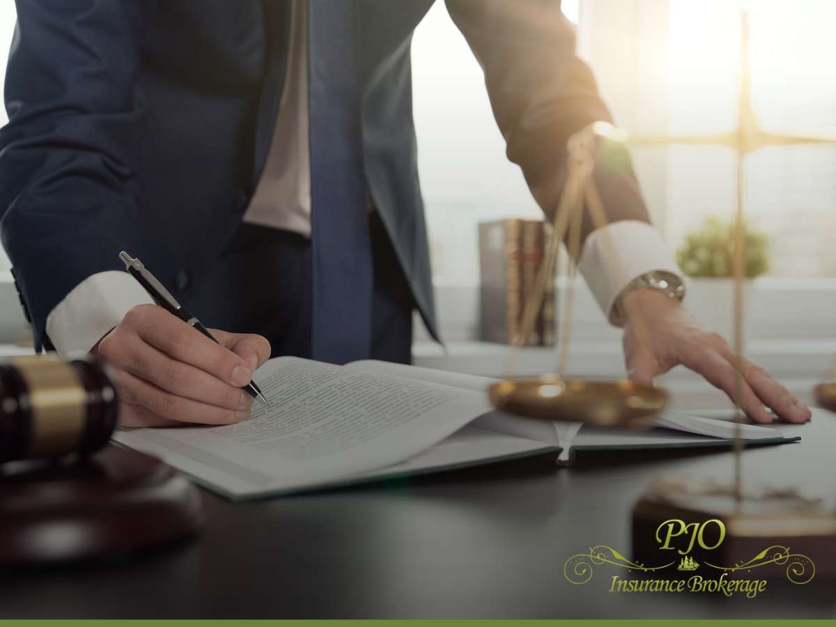 A lawyer writing in a book with scales of justice on the desk, representing Provisions Of Workers’ Compensation Coverage